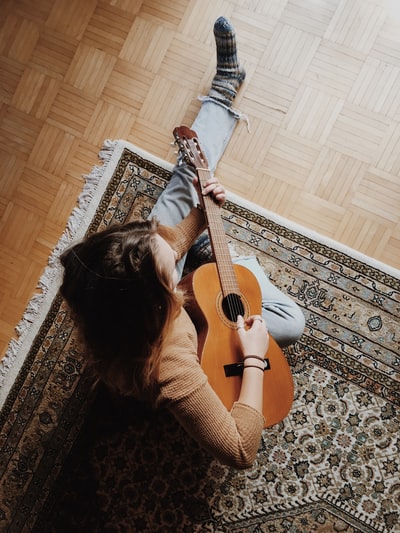 坐在地毯上弹吉他的人